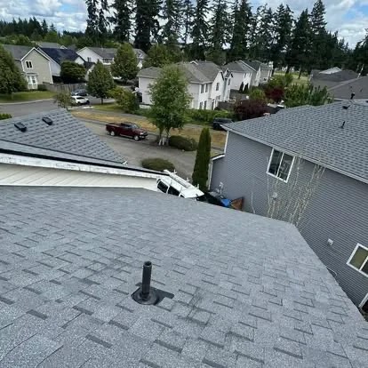 Completed residential shingle roof with clean flashing around a roof vent